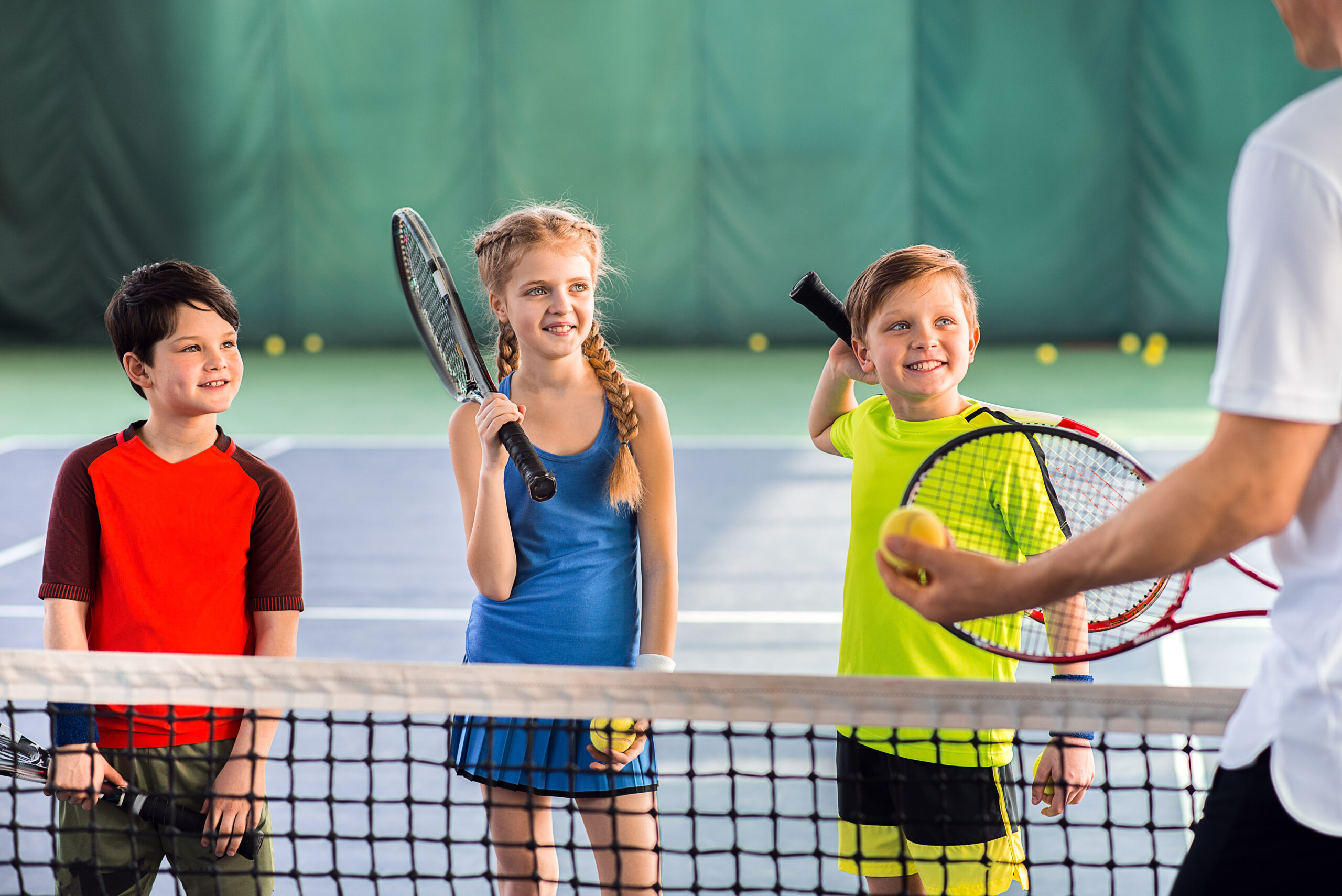 Joyful pupils learning to play tennis